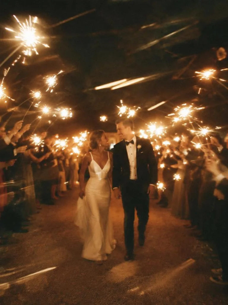 Couple walking through a sparkler send-off at night
