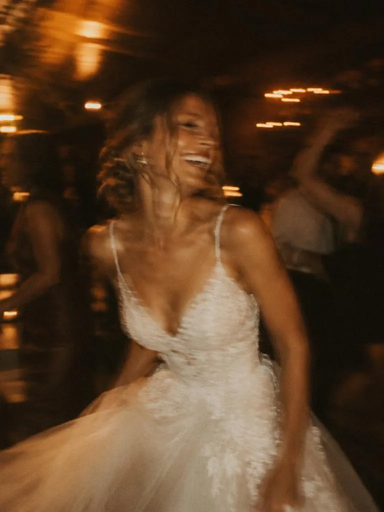 Bride laughing as she dances at her reception